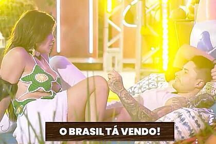 Jaquelline sentada de frente para Lucas, que está deitada olhando em direção a ela.