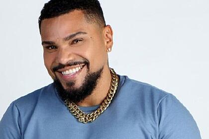 Naldo Benny sorrindo, de camisa azul, durante ensaio fotográfico