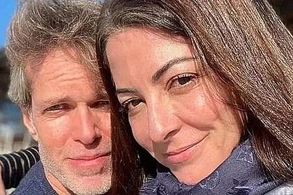 Ana Paula Padrão de cabelo solto, usando cachecol, abraçada com o marido, Gustavo Diament, durante viagem