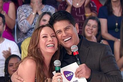 Regina volpato abraça cesar filho. Os dois estão sorrindo no palco do teleton 2023