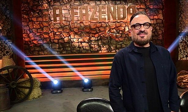 Rodrigo Carelli de paleto, camisa social e grava pretos, com a mão no bolso, sorrindo, com oculos de grau