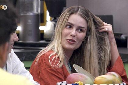 Yasmin Brunet sentada, de camisa marrom, mexendo no cabelo no BBB 24