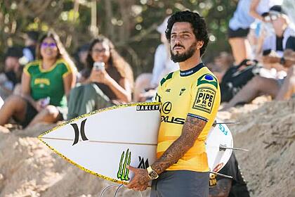 Filipe Toledo com uma prancha de surfe em baixo do braço