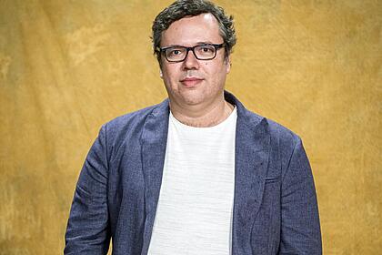João Emanuel Carneiro em foto de divulgação com fundo amarelo