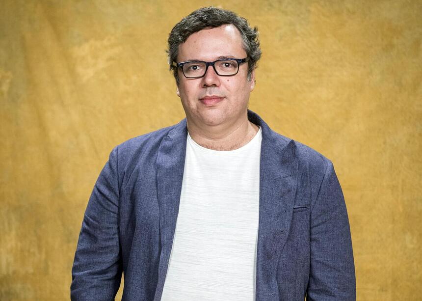 João Emanuel Carneiro em foto de divulgação com fundo amarelo