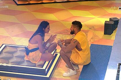 Juninho conversa com Alane, acocorados no chão do palco da festa do BBB 24
