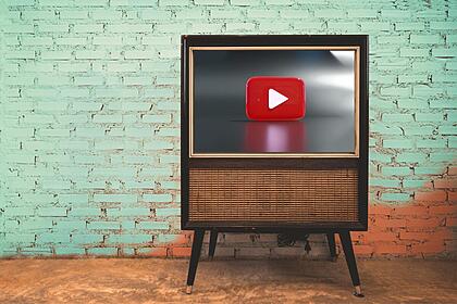 Televisão à frente de uma parede verde com o logo do Youtube