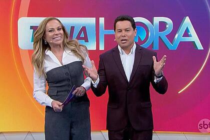 Cristina Rocha e Marcão do Povo sorrindo no cenário do Tá na Hora