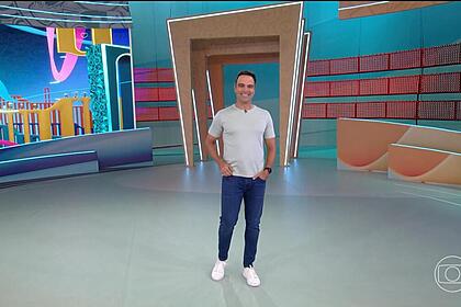 Tadeu Schmidt de camisa cinza e sorrindo antes de apresentar a dinâmica da semana no BBB 24