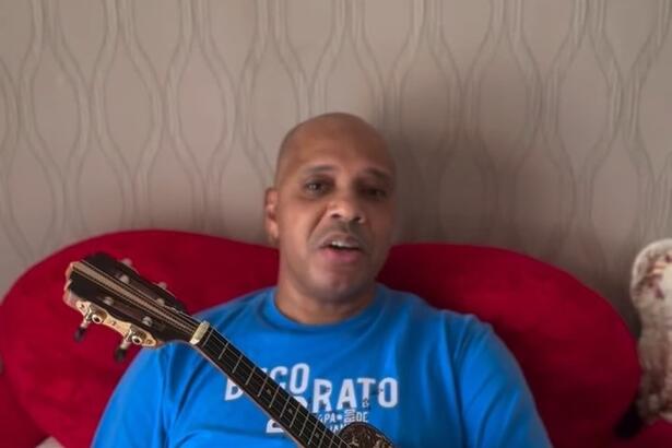 Anderson Leonardo do Molejo tocando cavaquinho deitado em uma cama