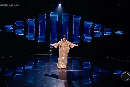 Carol Marques abre os braços no centro do palco do Canta Comigo 6