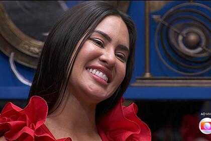 Isabelle, de vestido vermelho, sorrindo na sala do BBB 24 na final do programa