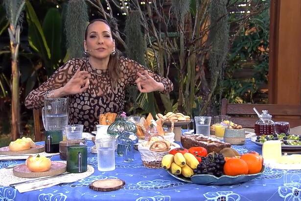 Maria Beltrão abre os braços sentada na mesa do É de Casa