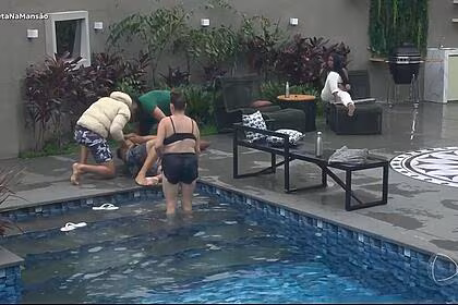 Bruno cardoso emborcado na lateral da piscina, sendo socorrido por conquisteiros no a grande conquista