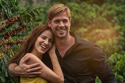 William Levy e Laura Londoño abraçados e sorrindo em um cafezal, nos bastidores da novela Café com Aroma de Mulher