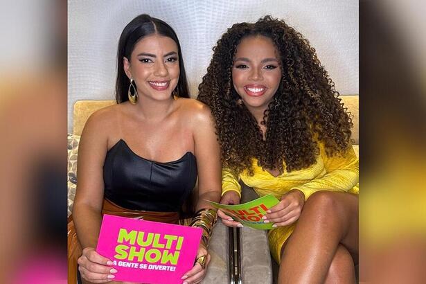 Fernanda e Pitel seguram fichas do Multishow nos bastidores do canal. As duas estão sorrindo