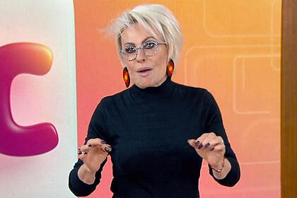 Ana Maria Braga em pé e gesticulando com as mãos no estúdio do Mais Você