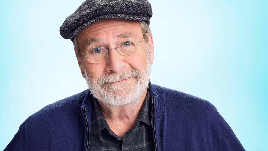 Martin Mull de óculos de grau e sorriso leve no rosto