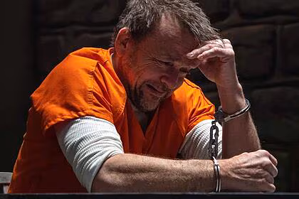 Homem com uniforme laranja algemado em uma prisão em cena do filme nefarious