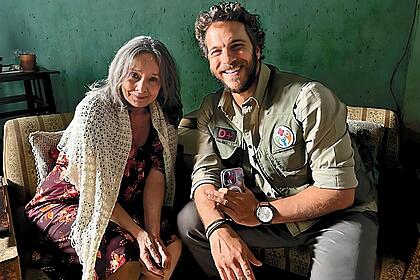 Débora Duarte sorrindo ao lado do ator Elam Lima nos bastidores das gravações de A Caverna Encantada