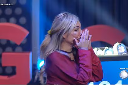 Lizi com a mão na boca chorando de felicidade ao vencer a prova da virada do a grande conquista 2