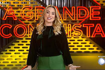 Rachel sheherazade sorrindo na frente do logo do a grande conquista 2