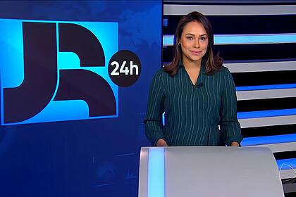 Salcy Lima sorrindo em frente ao telão do JR 24h, que venceu o SBT na audiência