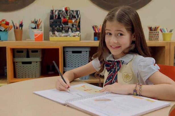 Anna em uma banca de escola na chamada de A Caverna Encantada