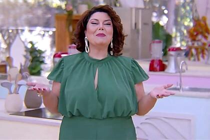 Fabiana Karla de vestido verde no cenário do Bake Off Brasil