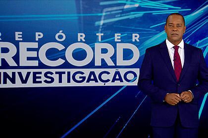 Luiz Fara Monteiro em frente ao logo do Repórter Record Investigação