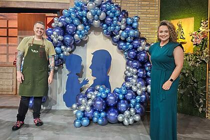 Chef Léo e Bianca posam com balões ao fundo