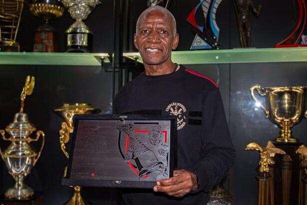 Adílio, segurando uma placa, em trecho de homenagem do Flamengo
