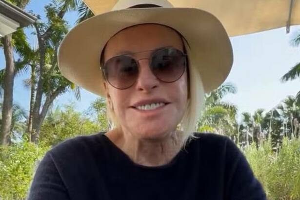Ana Maria Braga com um sorriso no rosto, com óculos e chapéu de sol