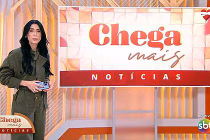 Michelle Barros de macacão verde apresentando o Chega Mais Notícias no SBT
