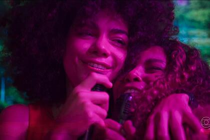 Zinha abraça e canta com uma mulher na balada em cena de Renascer