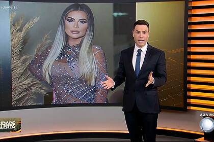 Luiz Bacci na frente do telão do Cidade Alerta que mostra a foto de Deolane Bezerra