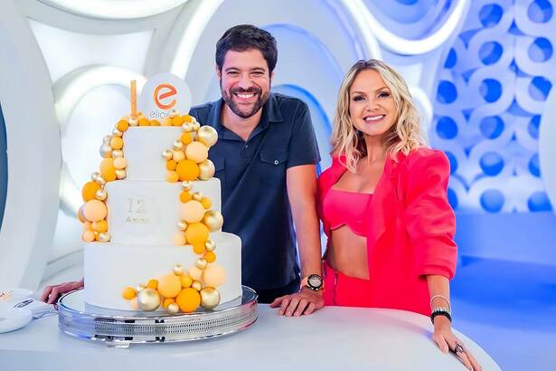 Ariel Jacobowitz ao lado de Eliana no estúdio do SBT. Os dois estão sorridentes ao lado de um bolo
