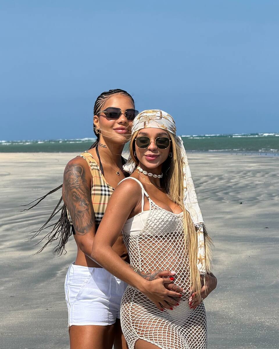 Brunna Gonçalves e Ludmilla em foto posada juntos na praia, com a cantora passando a mão na barriga da bailarina 
