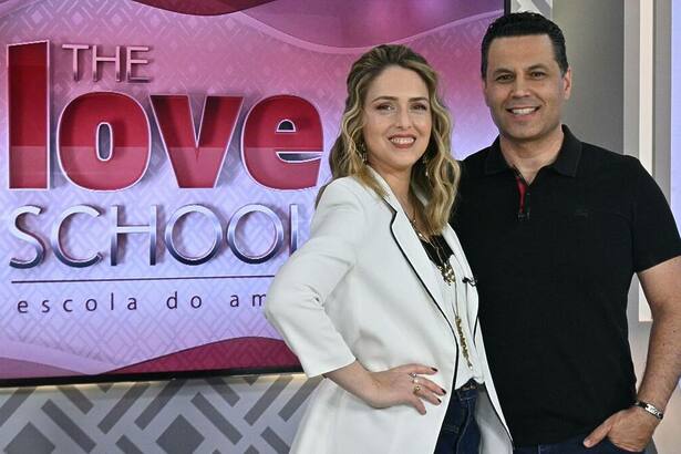 Renato e Cristiane Cardoso, em foto posada, juntos e abraçados na frente do telão do The Love School