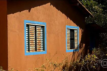 Parede de casa pintada com tinta à base de terra em reportagem do Globo Rural. As cores da casa são terrosas com detalhes azuis