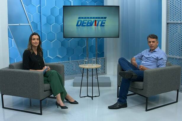Letícia Hamacher sentada no cenário do Aparecida Debate
