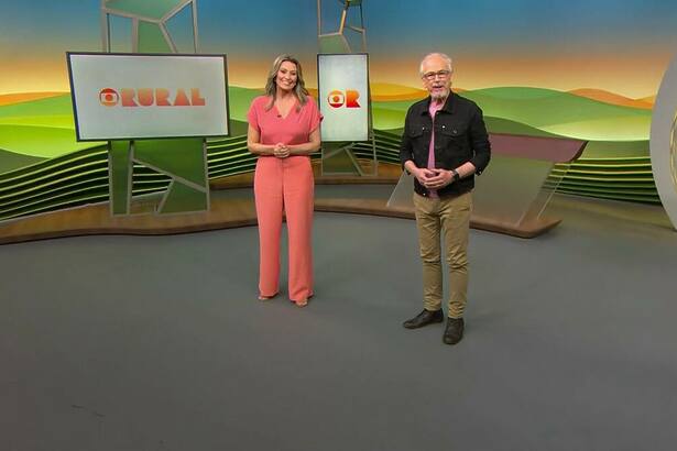 Cristina Vieira de conjunto salmão e Nélson Araújo com camisa presta e calça verde no centro do cenário do Globo Rural