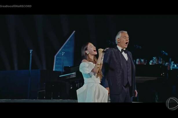 Mulher vestida de branco canta ao lado do Tenor Andrea Bocelli
