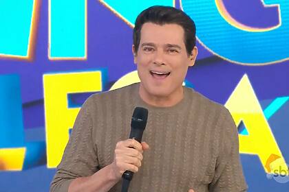 Celso Portiolli sorrindo e vestindo camisa cinza na apresentação do Domingo Legal, dia 15/12/2024