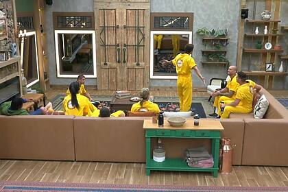 Peões vestidos de amarelo escutam sinal de recreio na sala de A Fazenda 16