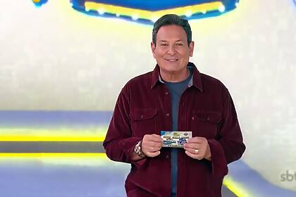 Luiz Ricardo está sorrindo no estúdio da Tele Sena Semanal segurando a edição de número 32