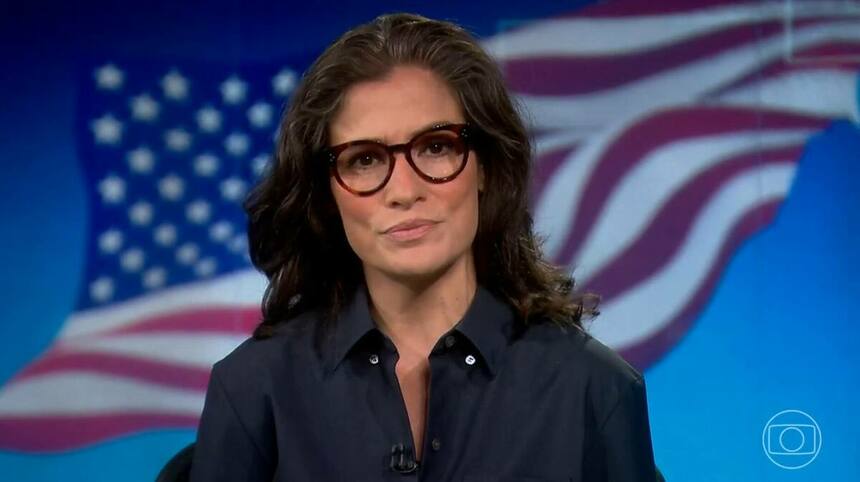 Renata Vasconcellos, em trecho do Jornal Nacional, com a bandeira dos Estados Unidos ao fundo