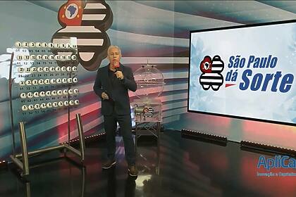 Apresentador do São Paulo dá Sorte de terno preto em frente ao globo de bolas no sorteio deste domingo 26/01/2025