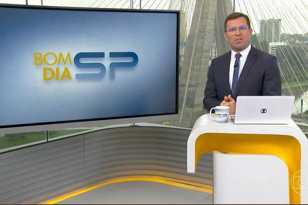 Rodrigo Bocardi veste terno preto e está por trás da bancada do Bom Dia SP