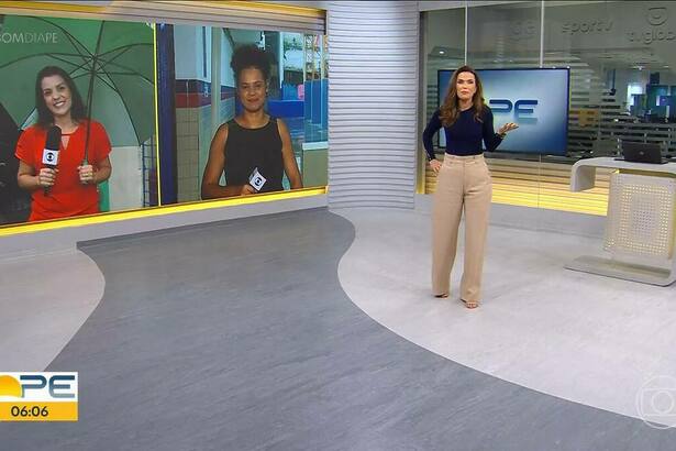 Clarissa Góes de blusa azul e calça nude andando pelo cenário do Bom Dia PE